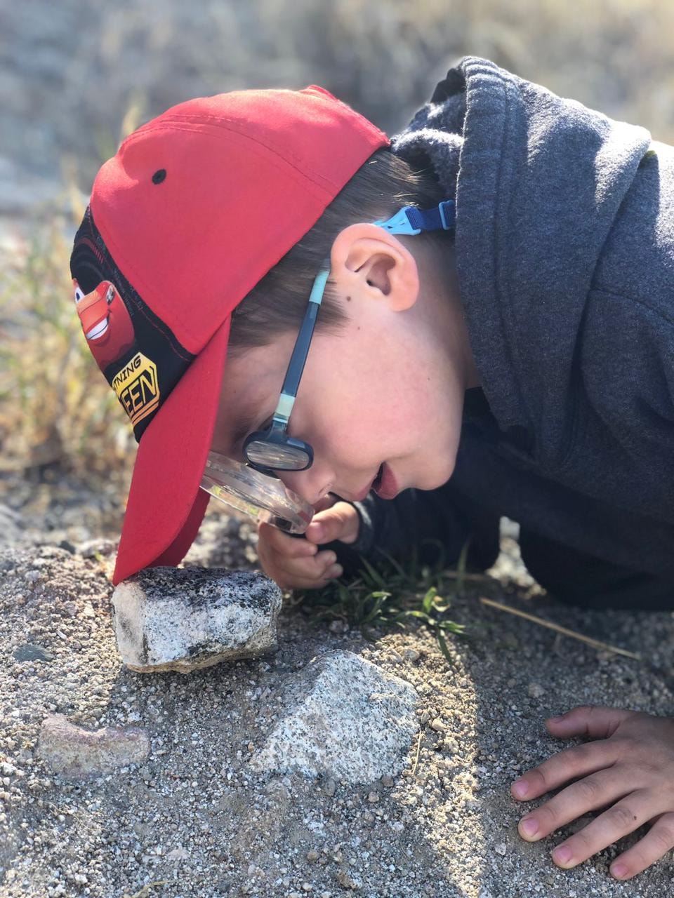Niño explorando rocas con lupa en campo